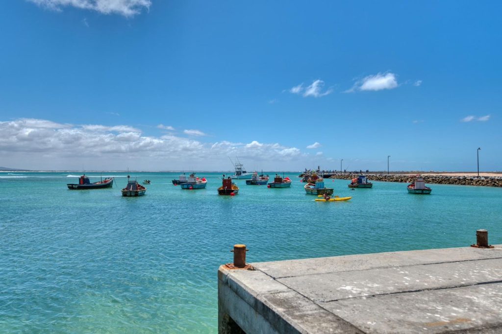 Wooden pier and small fishing boats seen at the Struisbaai harbour, located along South Africa's southernmost coastline