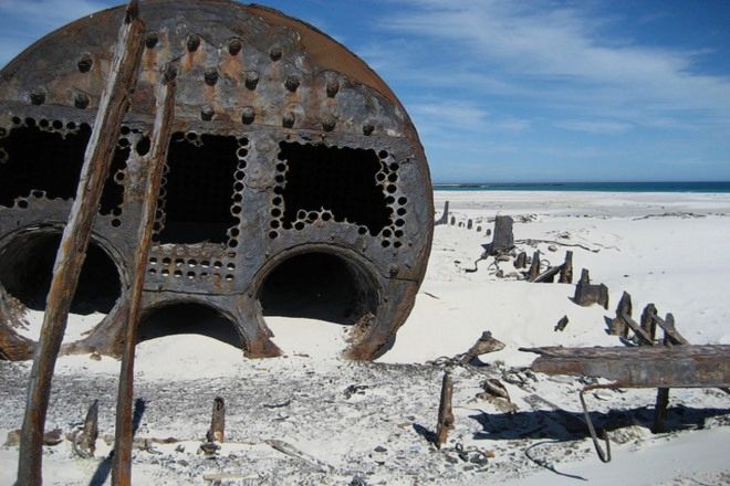 Rusted and broken ship sunken into the beach sand: shipwrecks along South Africa's coastline